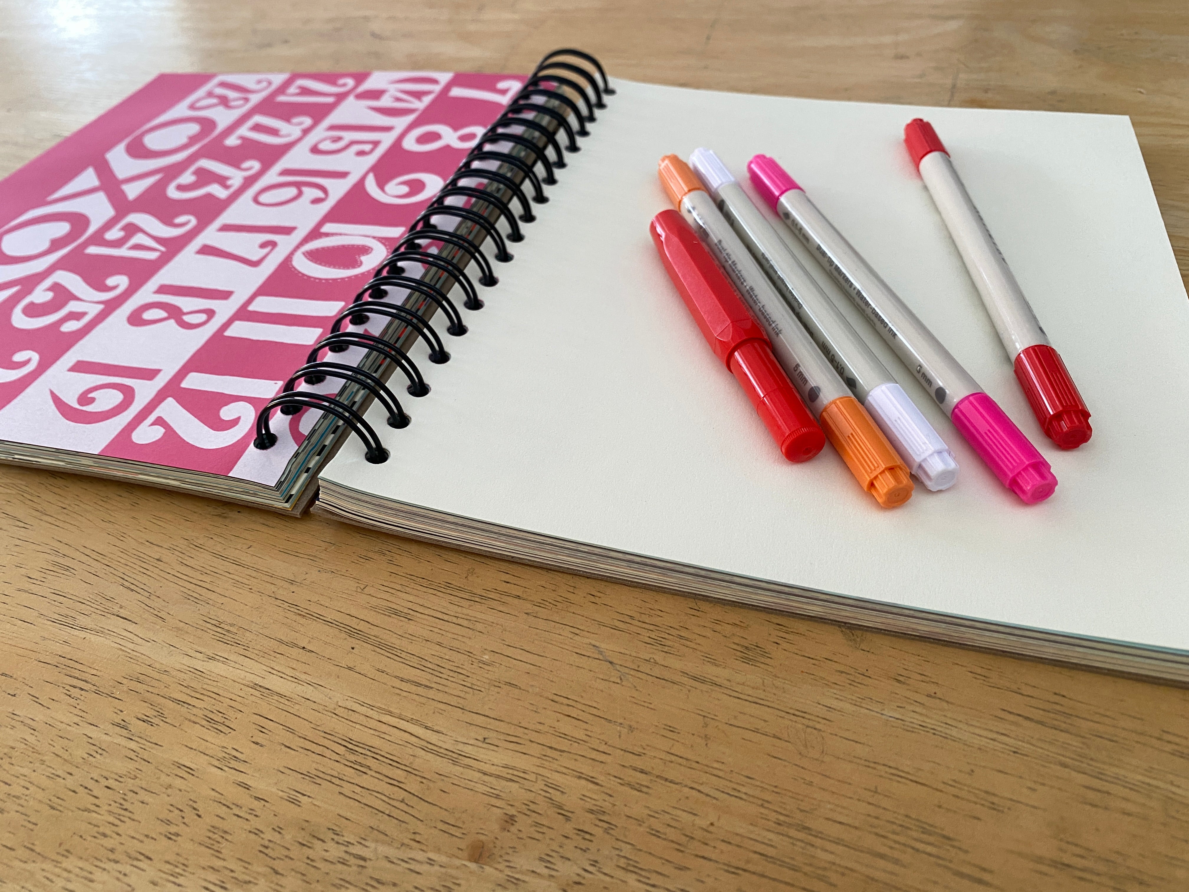 Notebook with colorful markers on a wooden surface