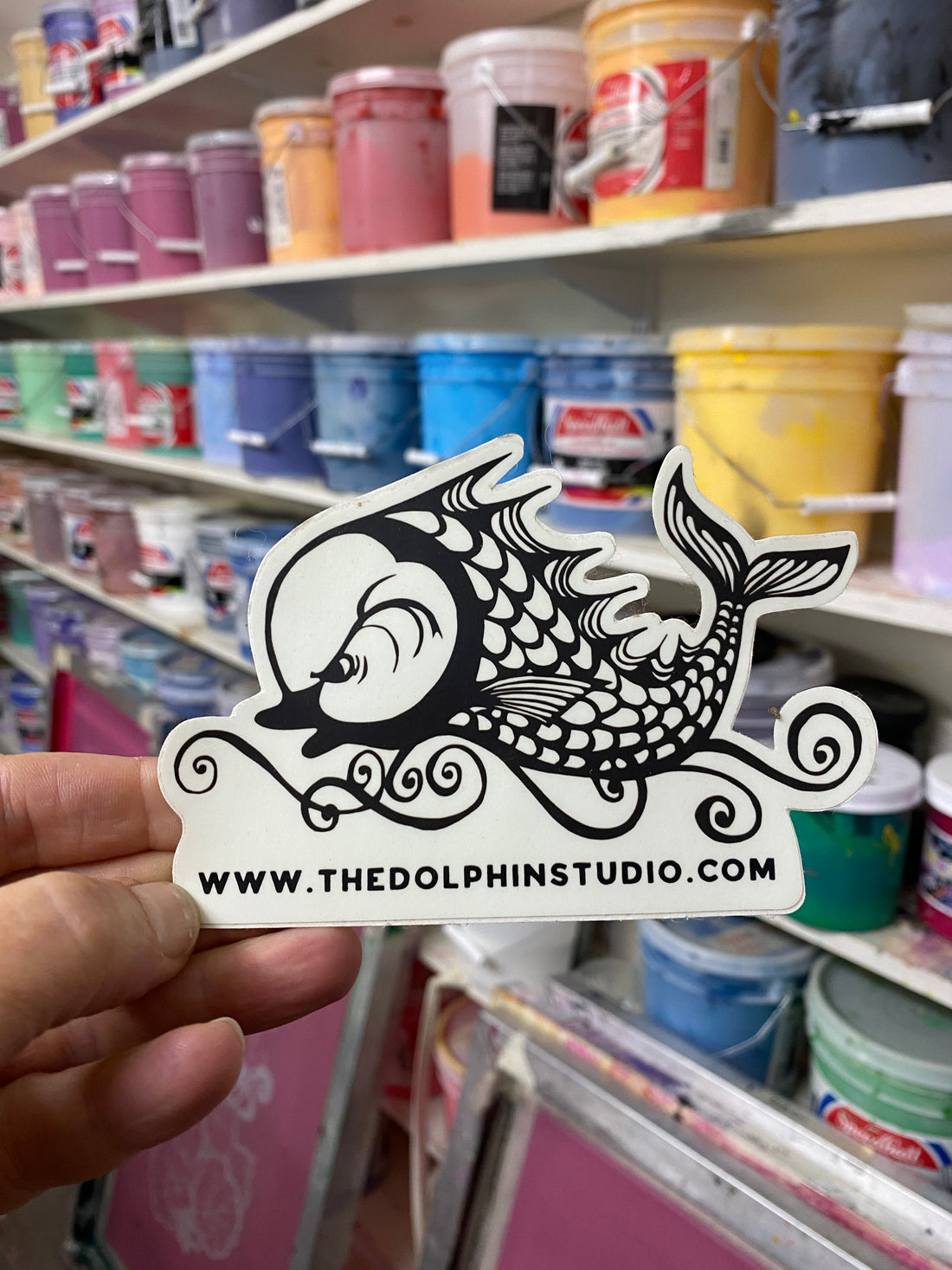 Dolphin Studio logo sticker in front of our wall of ink buckets